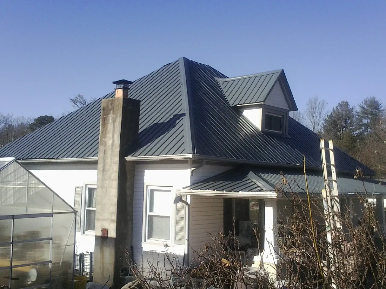 Dark blue standing seam metal roof on a white farmhouse with dormer — Slate & Tile Roof Repair by Roofing Brothers in Pacific Beach