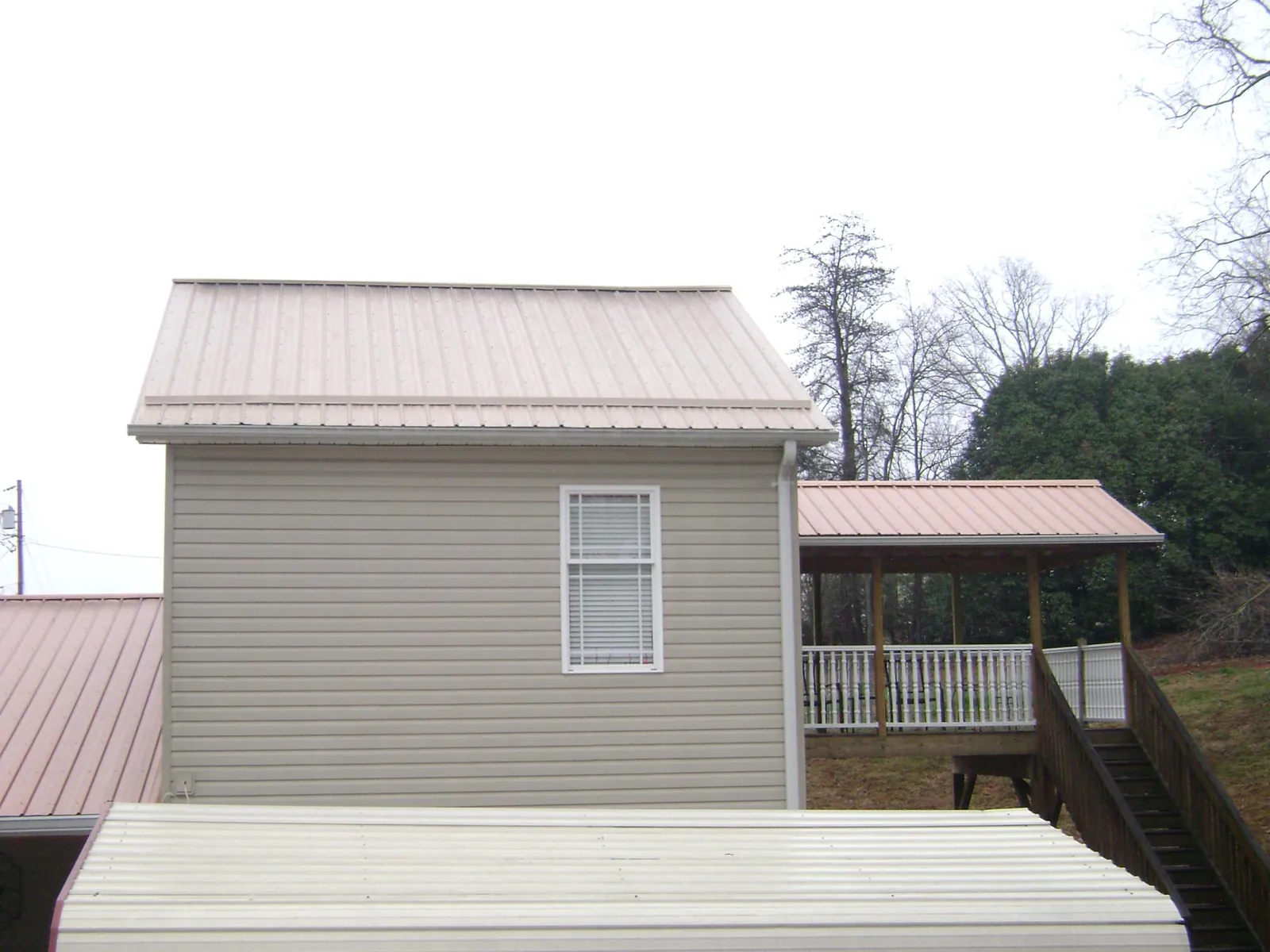 Tan metal roofs on a two story addition and attached porch, from a Roof Replacement job in Pacific Beach