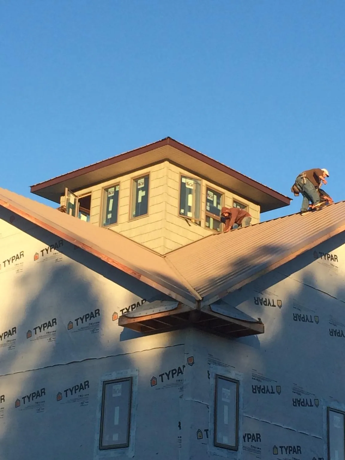 Roofers working around a rooftop cupola on a new metal roof at sunset — Roof Waterproofing in Pacific Beach by Roofing Brothers